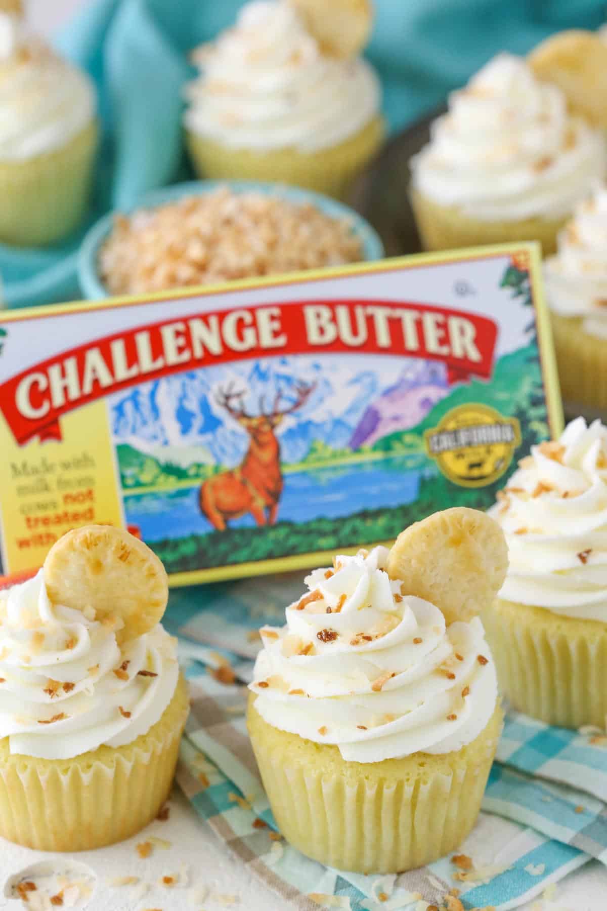 A couple coconut cream pie cupcakes next to a box of butter.